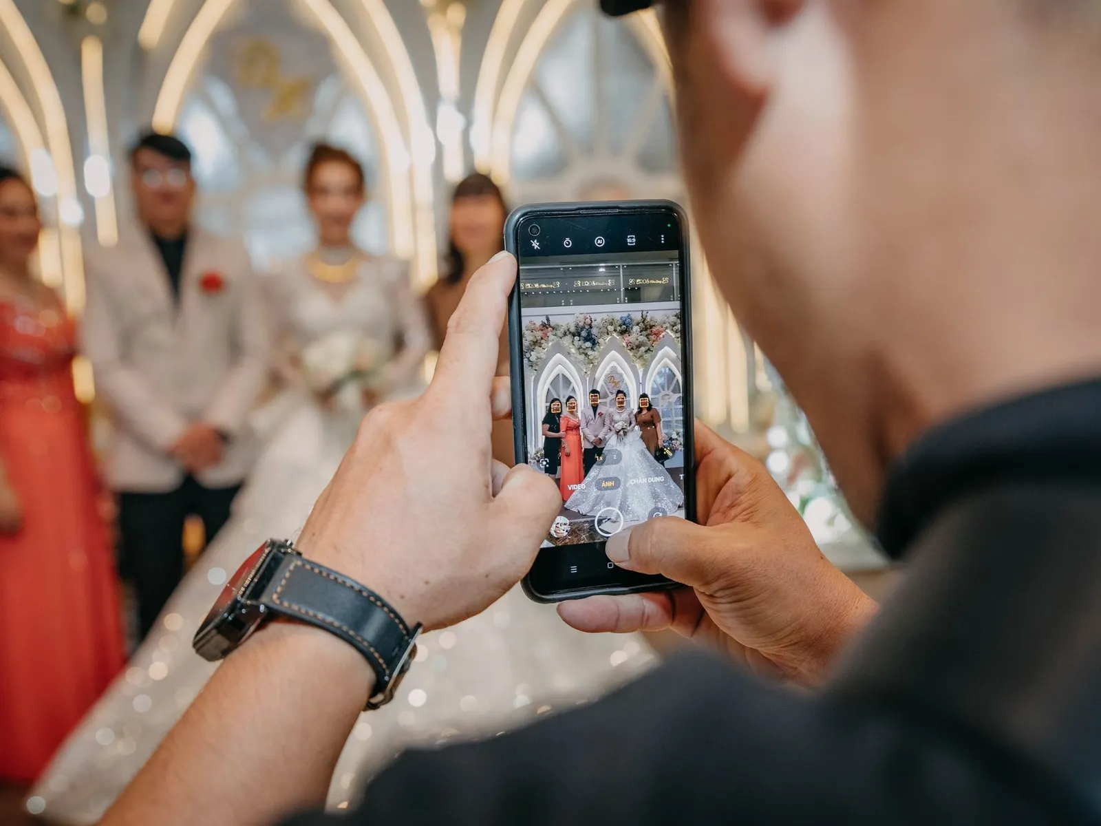 A guest photographing the couple with a phone at a wedding