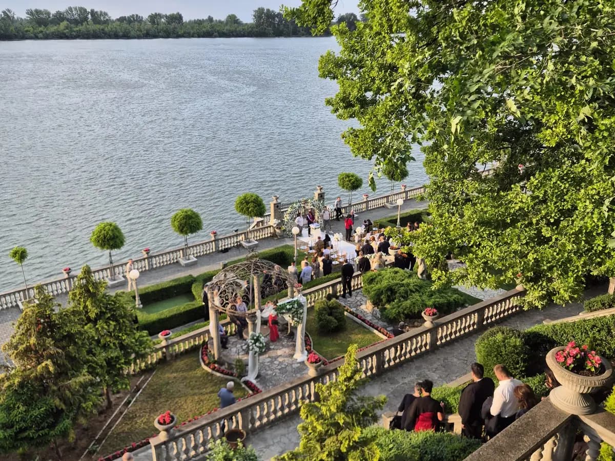 An outdoor wedding venue by the river seen from above, guests gathered around the ceremony