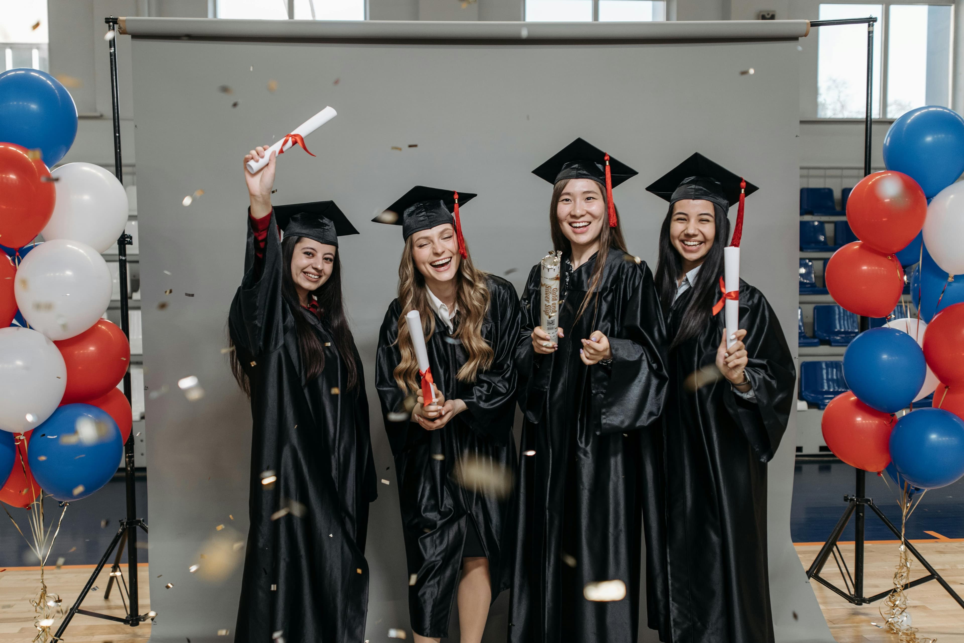 Graduation party setup with balloon backdrop, cap and gown, and guest prop table