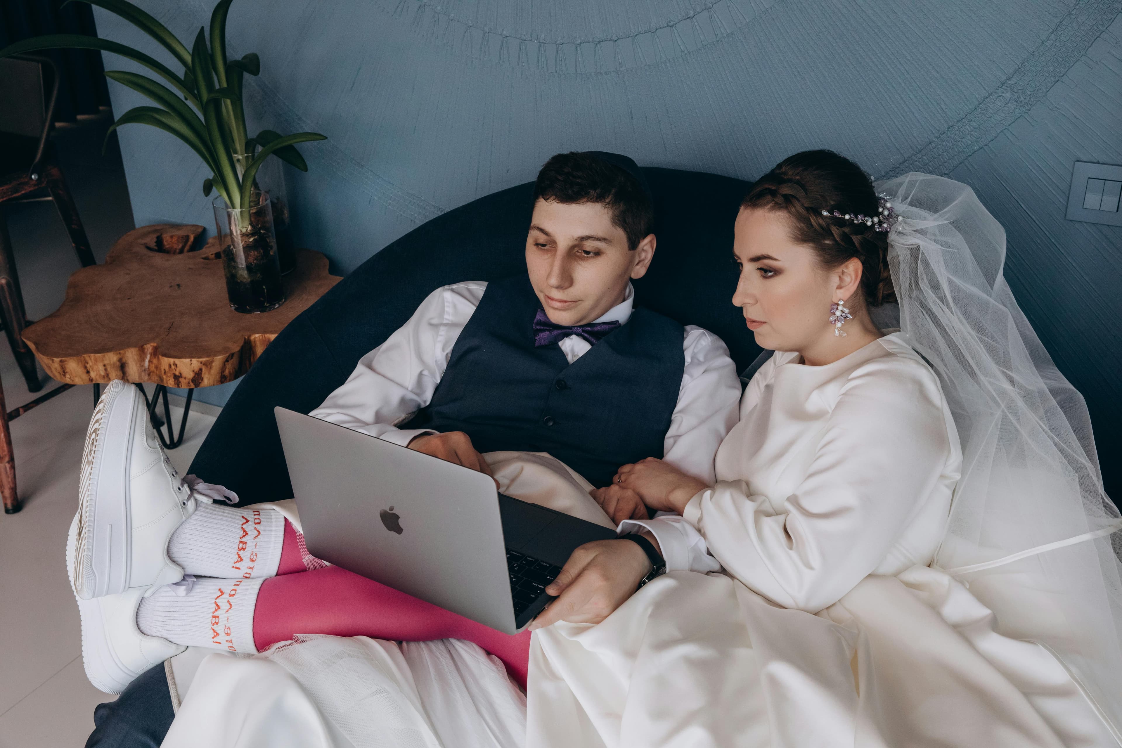 Couple reviewing wedding guest photos on a laptop after their reception