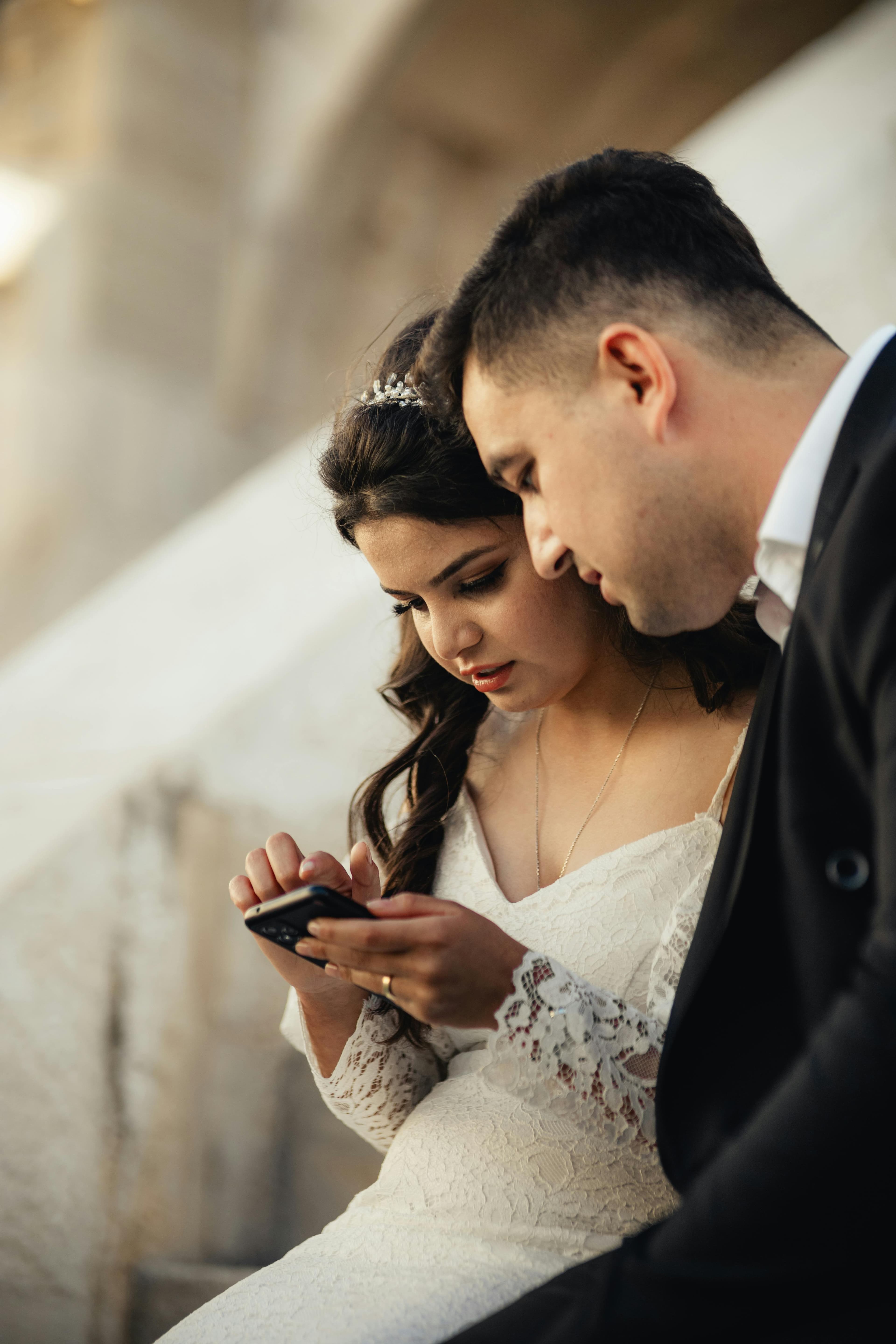 Couple reviewing guest wedding photos on a phone next to a WhatsApp group chat interface